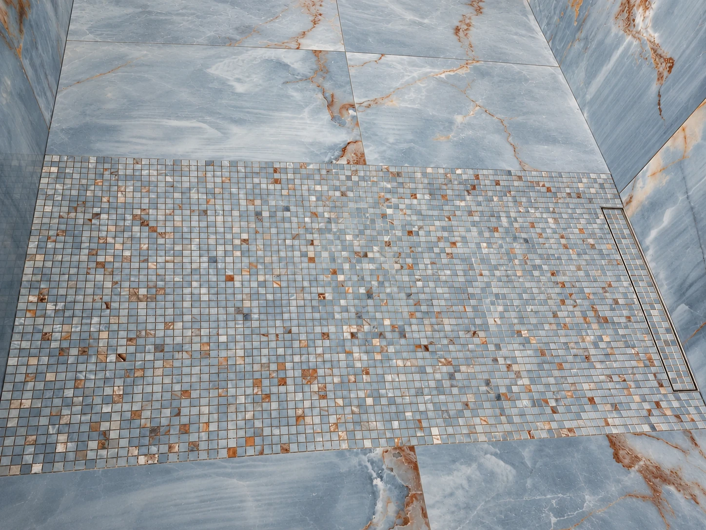 Blue mosaic shower floor with a linear drain and surrounding wall panels