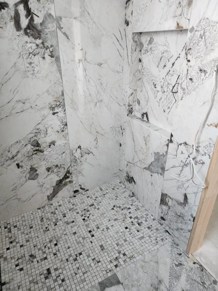 White and grey veined shower panels above a mosaic floor