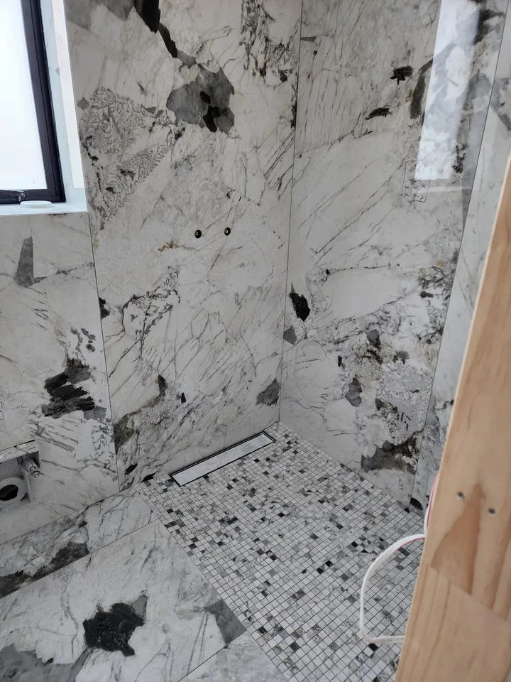 Veined shower interior with a window and linear floor drain
