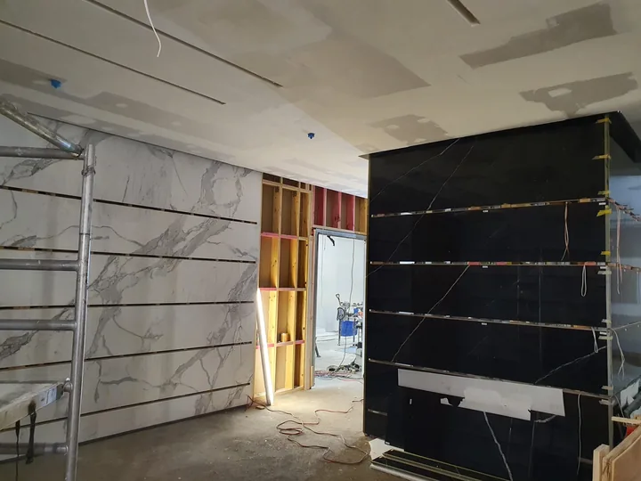 Contrasting veined wall finishes beside a doorway during installation